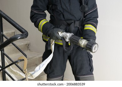 A Firefighter In Special Clothing Holds A Sleeve Line, Front View