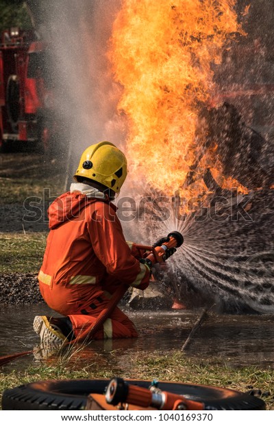 Firefighter is spraying water to extinguish the fire\
on a burning car.