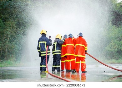 Firefighter spraying water to fire for heat protection, Team fireman training fighting fire.