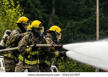 Firefighter Training. Fireman using water and extinguisher for fighting with fire flame in an emergency situation. Under danger situation all firemen wearing fire fighter gear for safety.