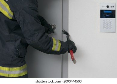 a firefighter tries to open the iron entrance door with an intercom in the entrance with a crowbar, close-up