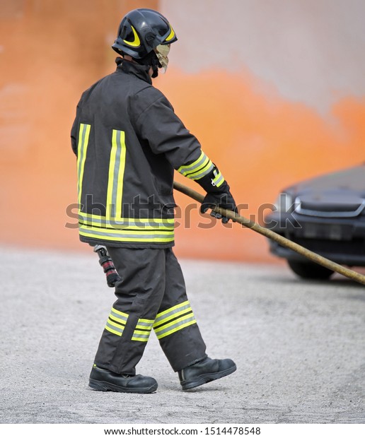 firefighter with uniform and helmet and a broken
car after the road
accident