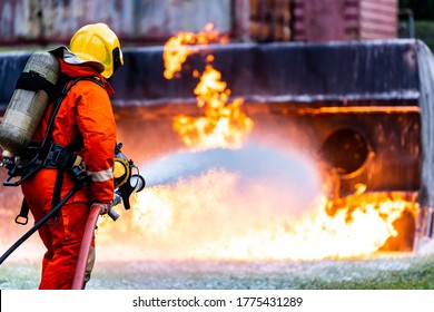 Firefighter Using Chemical Foam Fire Extinguisher To Fighting With The Fire Flame From Oil Tanker Truck Accident. Firefighter Safety Disaster Accident And Public Service Concept.