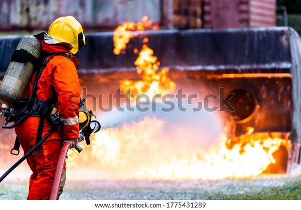 Firefighter using\
Chemical foam fire extinguisher to fighting with the fire flame\
from oil tanker truck accident. Firefighter safety disaster\
accident and public service\
concept.