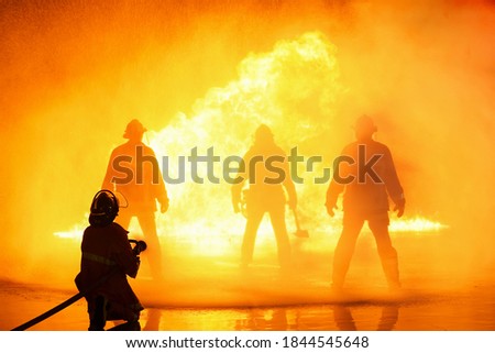 firefighter using extinguisher spraying high pressure water to fire for saving firefighters.