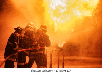 Firefighter using extinguisher or Twirl water fog type fire extinguisher to spray water from hose for fire fighting with fire flame on fuel and control fire for safety in plant of industrial area.