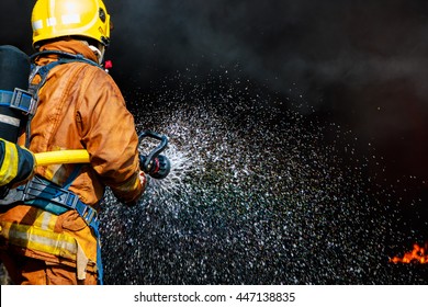 Firefighter Using Extinguisher And Water From Hose For Fire Fighting, Firefighter Spraying High-pressure Water To Fire