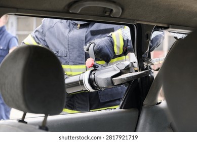 Firefighter Using Hydraulic Rescue Tool For Vehicle Extrication During Emergency Car Accident Response