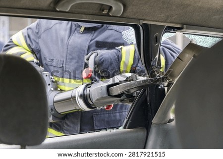 Firefighter Using Hydraulic Rescue Tool To Extricate Passenger From Crashed Car With Broken Glass