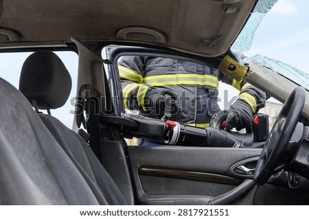 Firefighter Using Hydraulic Rescue Tool To Extricate Occupant From Crashed Car At Accident Scene