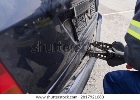 Firefighter Using Hydraulic Rescue Tool Jaws Of Life To Open Crashed Car Trunk During Extrication