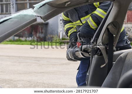 Firefighter Using Hydraulic Rescue Tool To Extricate Passenger From Crashed Car During Emergency Response