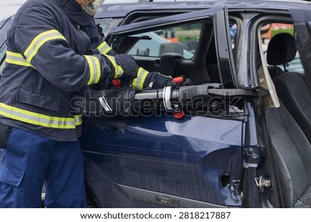 Firefighter Using Hydraulic Rescue Tool To Extricate Passenger From Crashed Car During Emergency Response