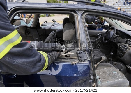 Firefighter Using Jaws Of Life To Cut Open Damaged Car Door During Vehicle Rescue Training