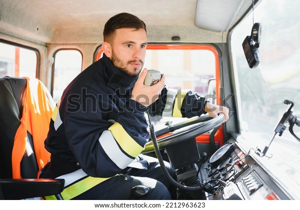 Firefighter using portable radio set in fire truck,\
space for text.
