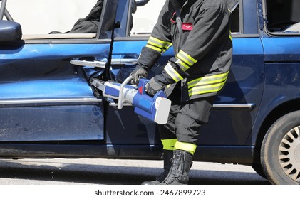 Firefighter using powerful hydraulic shears to pry open the door of a wrecked car