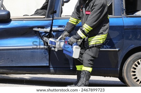 Firefighter using powerful hydraulic shears to pry open the door of a wrecked car