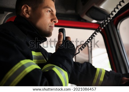 Firefighter using radio set while driving fire truck, closeup