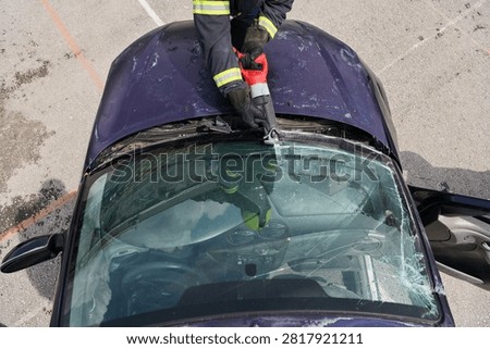 Firefighter Using Rescue Tool To Cut Windshield During Vehicle Extrication After Car Accident