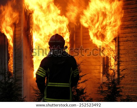 Firefighter watches old, abandoned house burning down.
