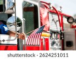 A firefighter waves an American flag from the driver