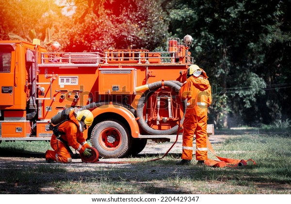 Firefighter
wearing safety fire suite near water emergency truck with equipment
with water hose over shoulder equipment and accessories is fire
safety accident protection safety
concept.
