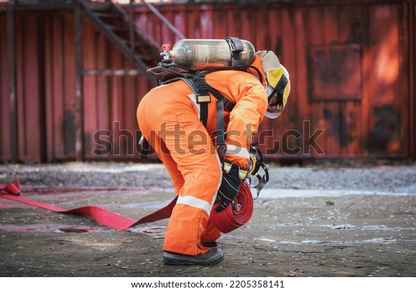 Firefighter\
wearing safety fire suite near water emergency truck with equipment\
with water hose over shoulder equipment and accessories is fire\
safety accident protection safety\
concept.