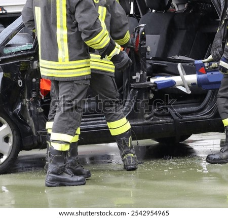 firefighters in action during rain using powerful hydraulic shears to cut through strong car metal