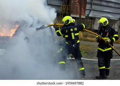 Firefighters With Breathing Apparatus Extinguish A Car That Is Completely Engulfed In Fire