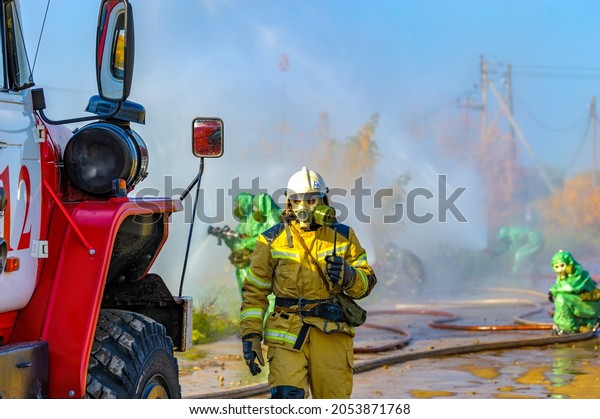 Firefighters in chemical protection suits eliminate an\
ammonia leak and extinguish a fire at a chemical plant. Rescue\
operation to create water barriers to toxic chemical cloud after\
the accident. 