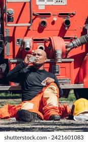 Firefighters  cooling down by drinking water among the smoke. fireman drinking water from bottle while sitting on staircase in firefighers trainning. Fireman rest and drinking water in work site.