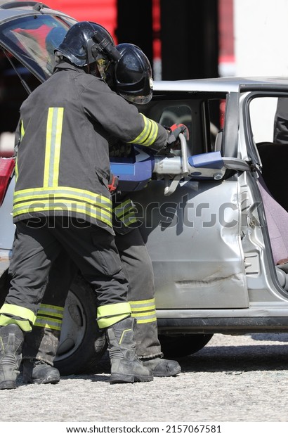 firefighters cutting the sheets of the crashed\
car with a powerful hydraulic shear to free the injured after the\
car accident