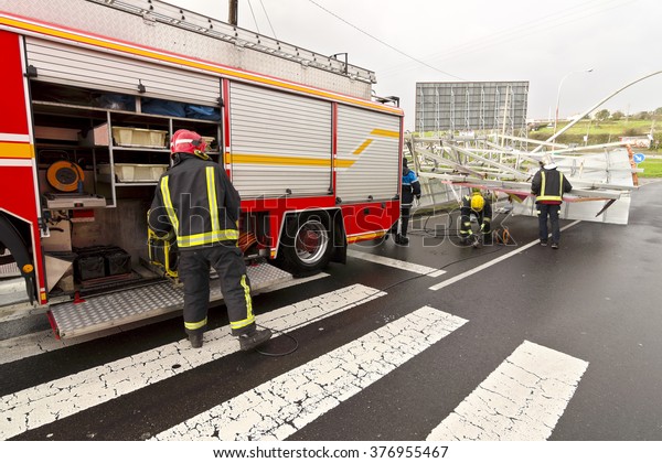 firefighters with electric\
grinder for remove the  billboard demolished by wind in the highway\
in stormy day