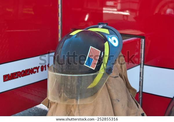 firefighter\'s helmet on\
coat by red fired\
truck