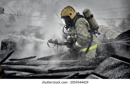 Firefighters with the inscription on the back in Russian " fire protection. Emercom of Russia" extinguish a fire on the roof of a house on a frosty winter day
