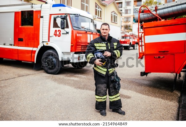 Firefighters man in a protective\
suit near fire truck. Protection, rescue from danger. Fire\
station.