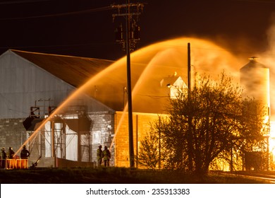Firefighters Protecting Structures with Two Streams of Water in the Night