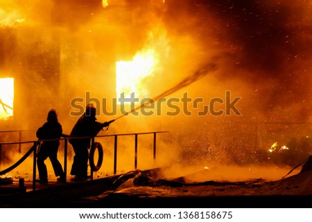 Firefighters spraying high pressure water to burning house.  Conflagration. Ukraine.
