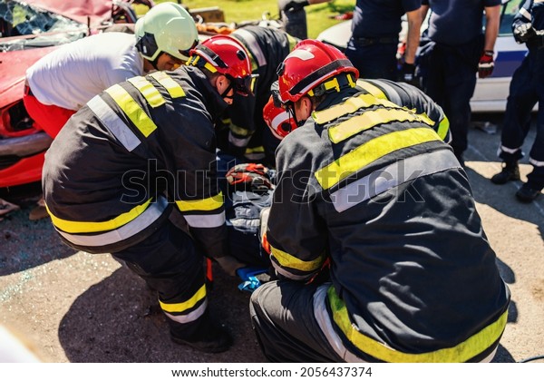 Firefighters taking care of other firefighter and\
pulling him from crashed\
car.