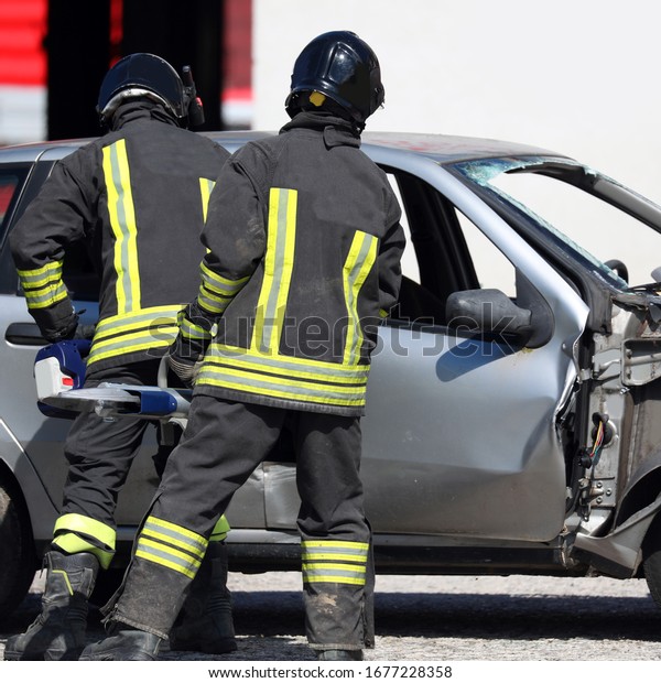 firefighters with uniofmr and helmet open a\
broken car after the road\
accident