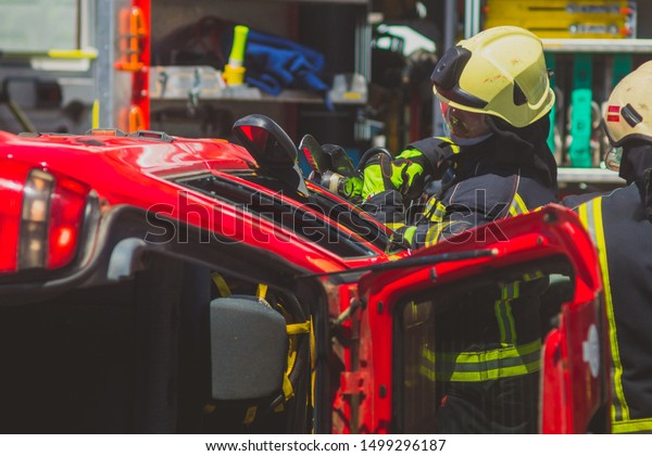 Firefighters using a hydraulic jaws of life or
scissors to cut the crashed car open to save the driver caught
inside. Emergency situation in a road
crash