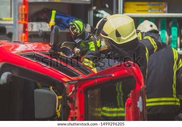 Firefighters using a hydraulic jaws of life or\
scissors to cut the crashed car open to save the driver caught\
inside. Emergency situation in a road\
crash
