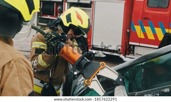 Firefighters using jaws of life to\
extricate trapped victim from the car. High quality\
photo