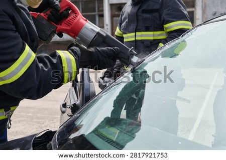 Firefighters Using Saw To Cut Windshield During Car Rescue And Extrication Operation