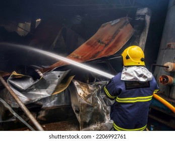 Firefighters Using Water Fog Fire Extinguisher To Fighting With The Fire Flame In Large Building. Firefighter And Industrial Safety Disaster And Public Service Concept.