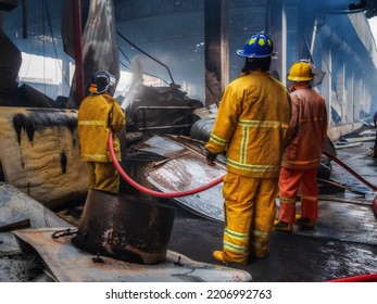 Firefighters Using Water Fog Fire Extinguisher To Fighting With The Fire Flame In Large Building. Firefighter And Industrial Safety Disaster And Public Service Concept.