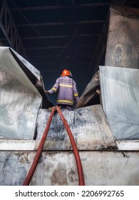 Firefighters Using Water Fog Fire Extinguisher To Fighting With The Fire Flame In Large Building. Firefighter And Industrial Safety Disaster And Public Service Concept.