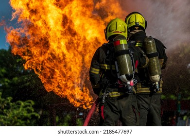 Firefighters Wearing Fire Fighter Suit For Safety And Using Twirl Water Extinguisher For Fighting The Fire Flame In Emergency Situation.. - Safety Firefighter And Industrial Concept.