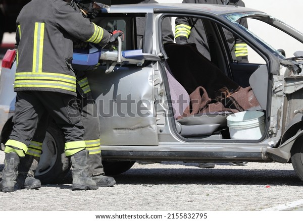 firefighters working group cutting the sheets of\
the crashed car with a powerful hydraulic shear to free the injured\
after the car\
accident