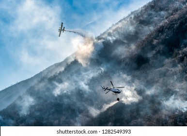 Firefighting Aircraft and Helicopter dropping the water for fighting a fire on mountain, above Lake Ghirla in Valganna, province of Varese, Italy